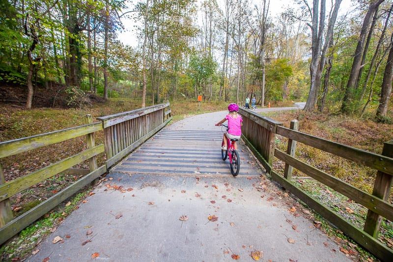 girl bike riding through a park trail