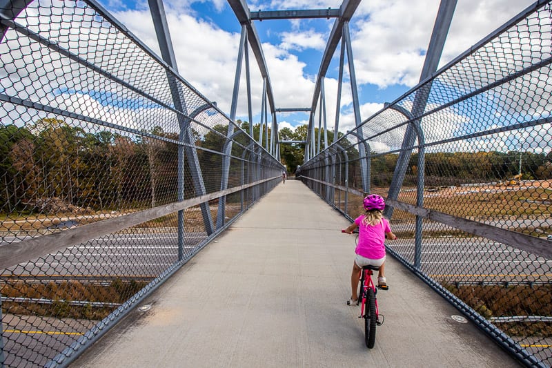 A little girl riding a bike across a bridge