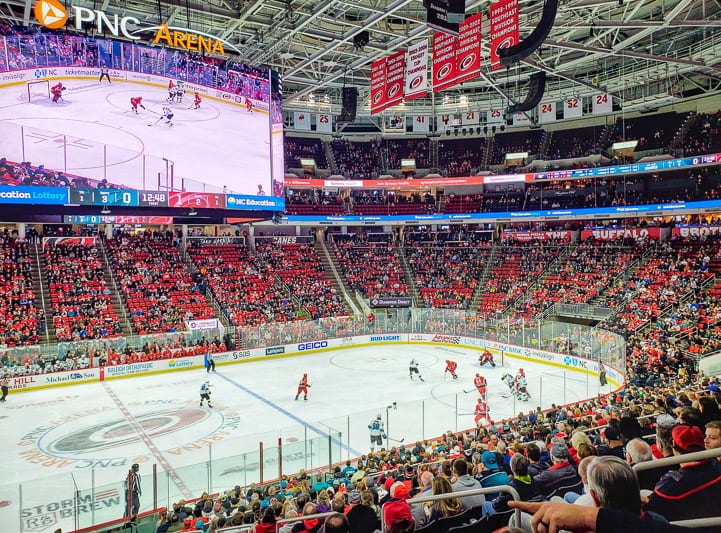 A large crowd of people watching an ice hockey game in an arena