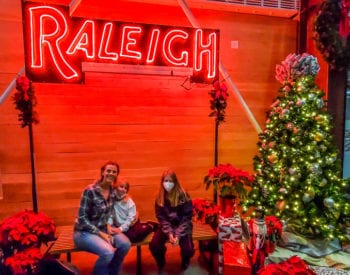 people sitting on a bench next to a christmas tree