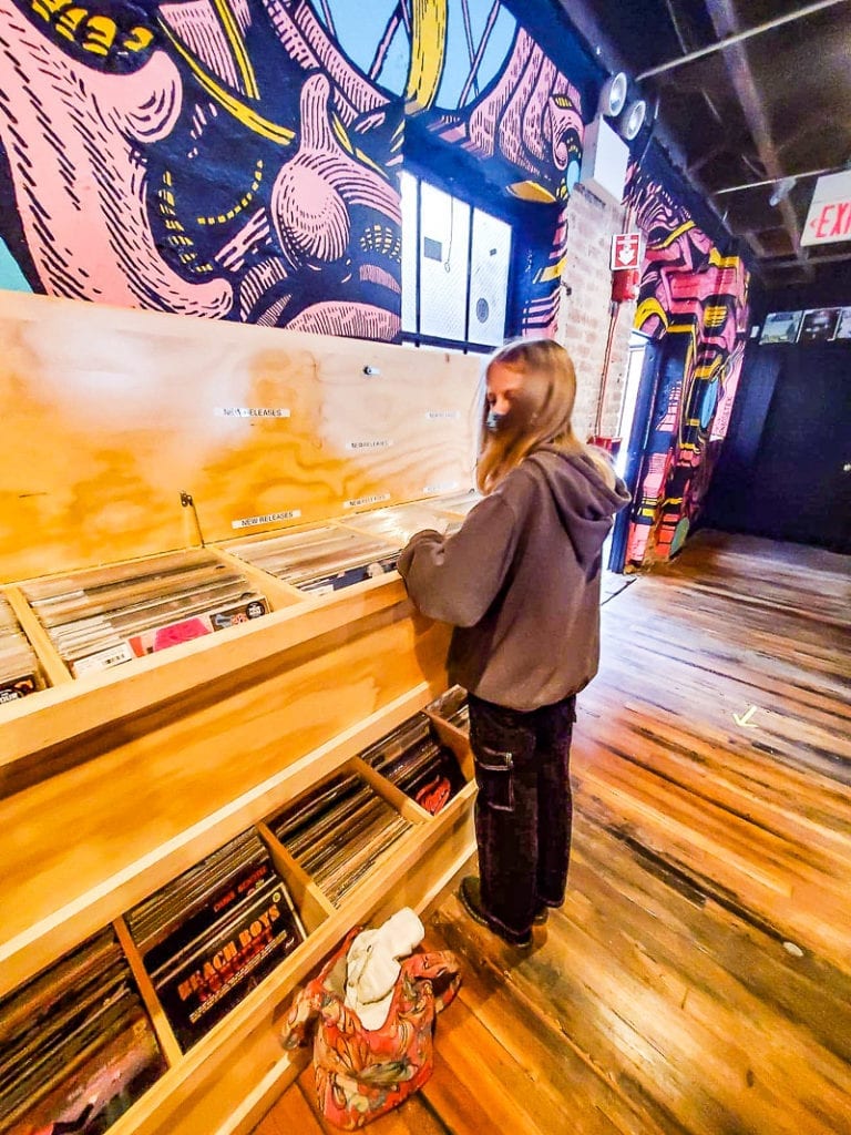 girl looking through vinyls at a record store