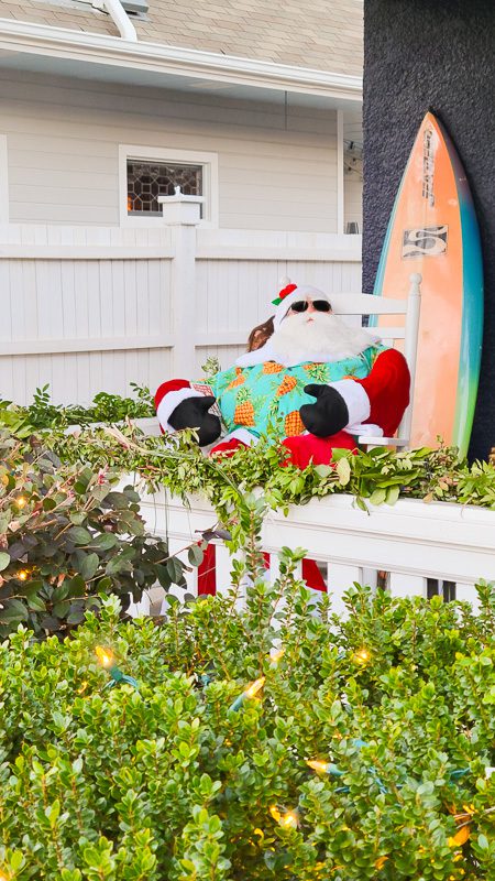 santa sitting on porch behind a surfboard