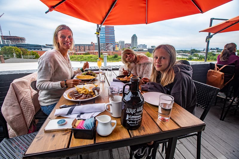 people smiling at camera sitting at table with views of raleigh at Wye Hill Kitchen & Brewing