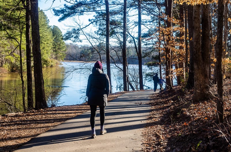 a person walking next to a body of water surrounded by trees