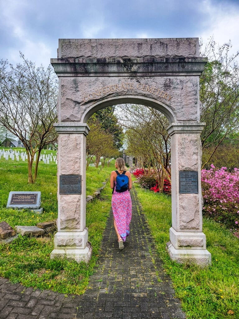 caroline walking under stone arch at Historic Oakwood Cemetery