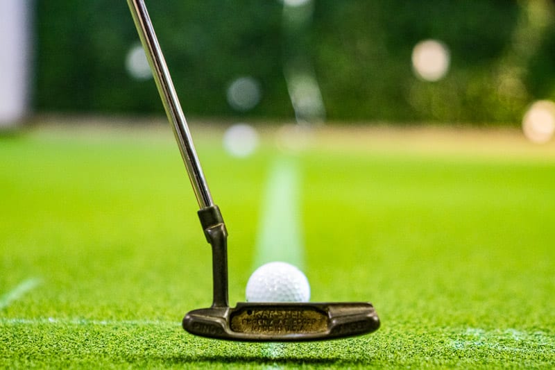 A close up of a golf ball and club