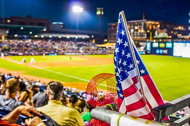 American flag with baseball game in background