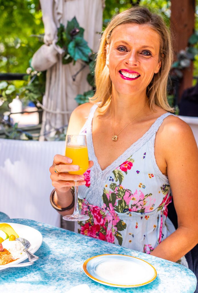 woman smiling at the camera while holding a drink