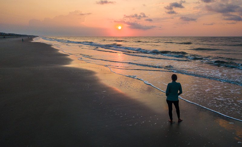 woman standing on Ocean Isle beach looking at sunrise a