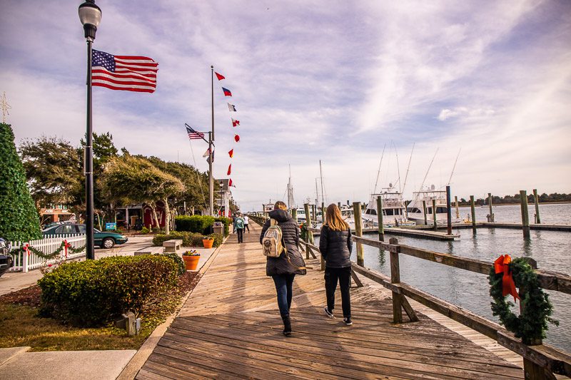 A group of people walking down a board walk next to a body of water