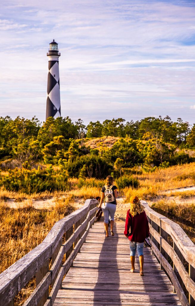 A group of people walking on a bridge towards a lighthouse