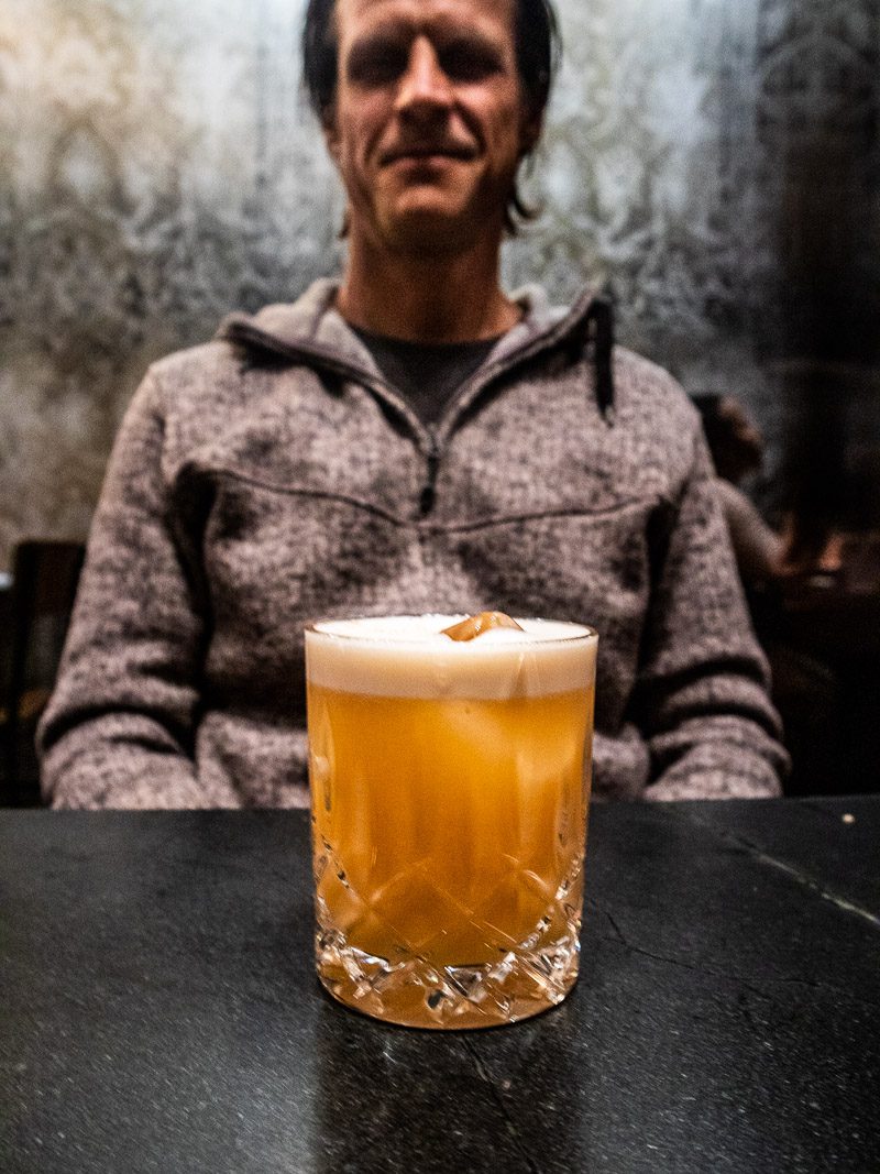 close up of a drink with a man sitting in the background