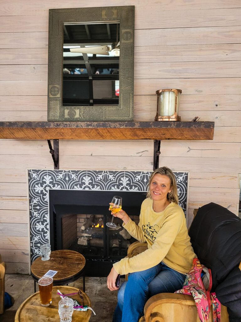 woman sitting near fireplace with wine in hand at Vita Vite Wine Bar