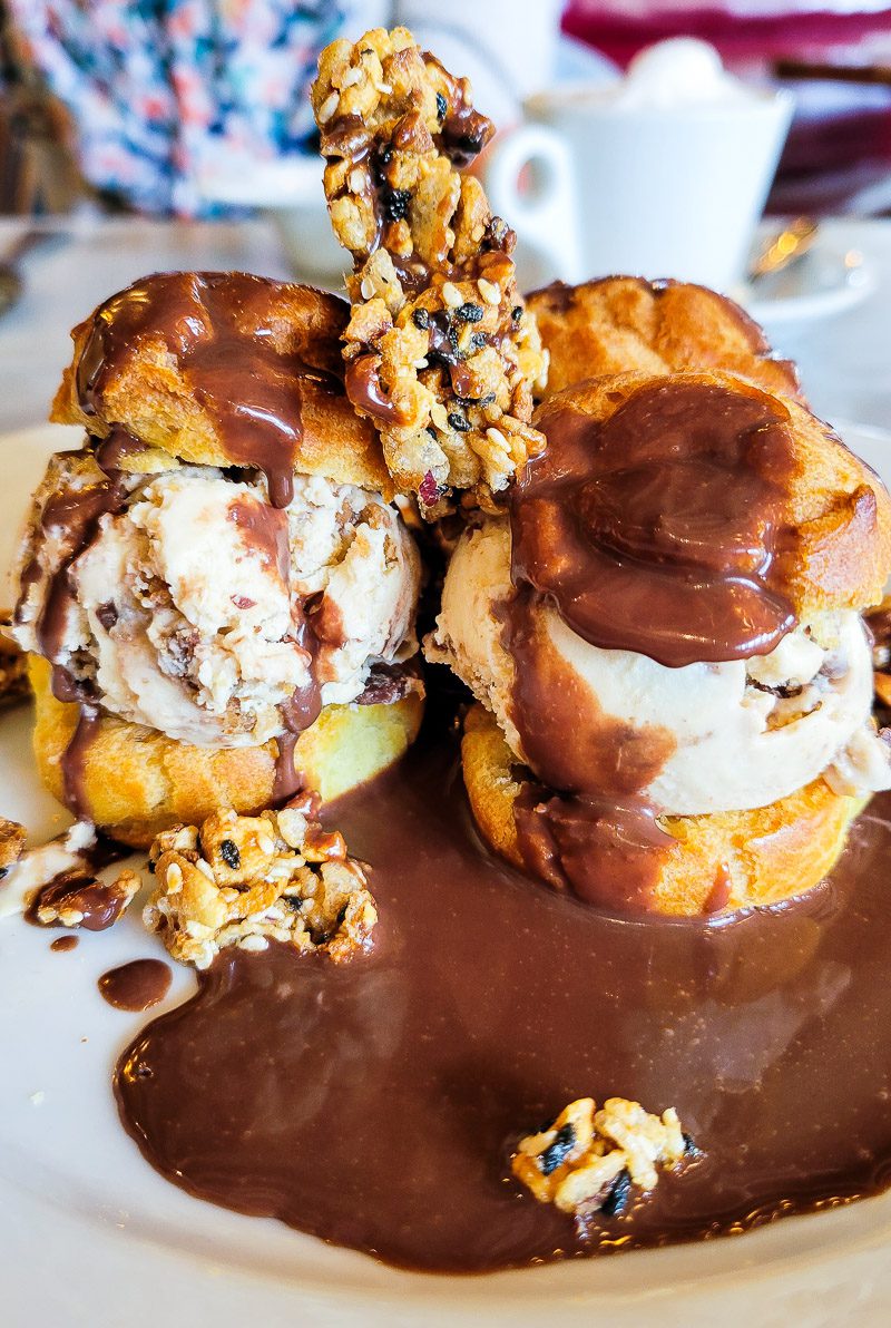 A plate of pastries and ice cream drizzled with chocolate
