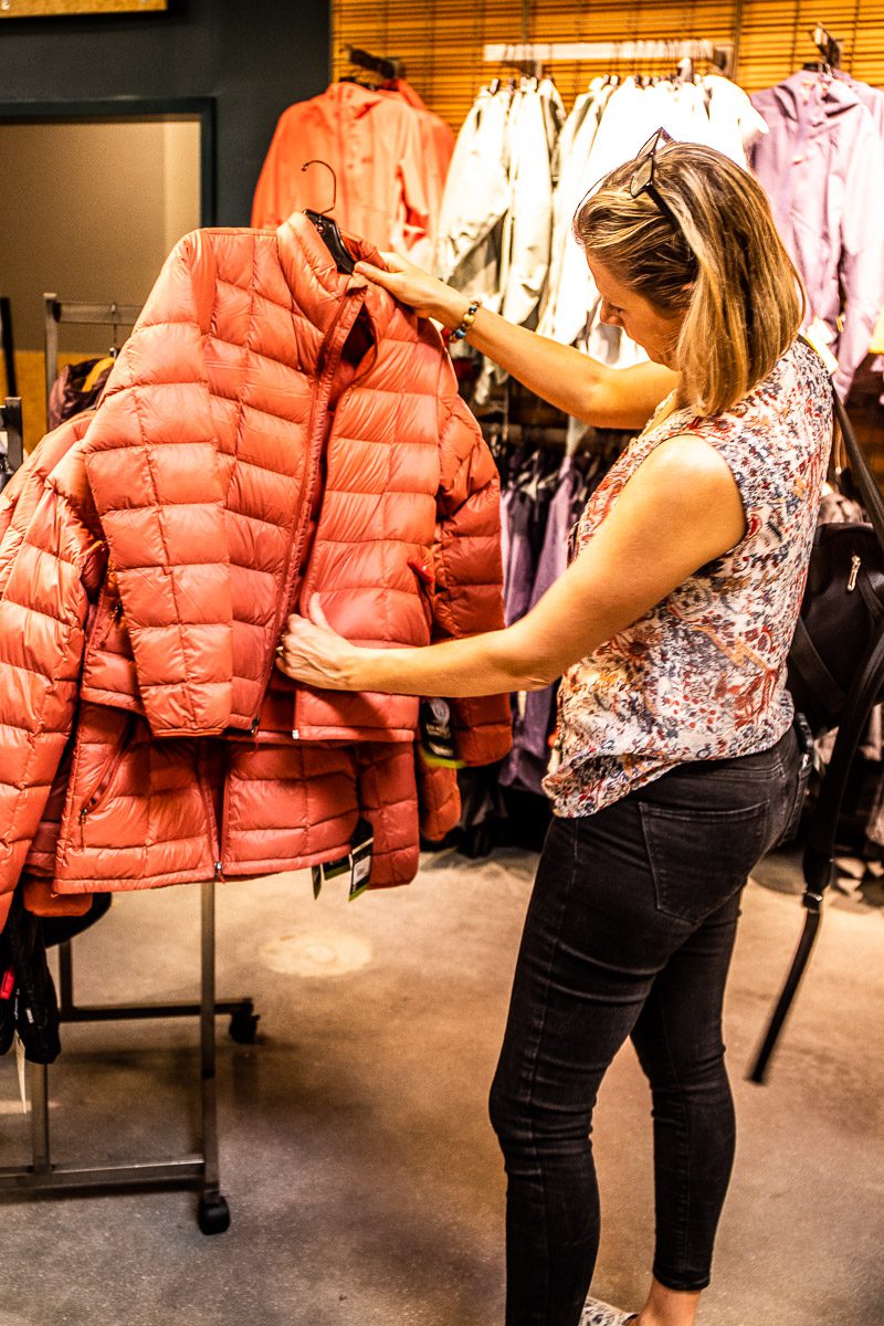 A woman looking at a red jacket in a store