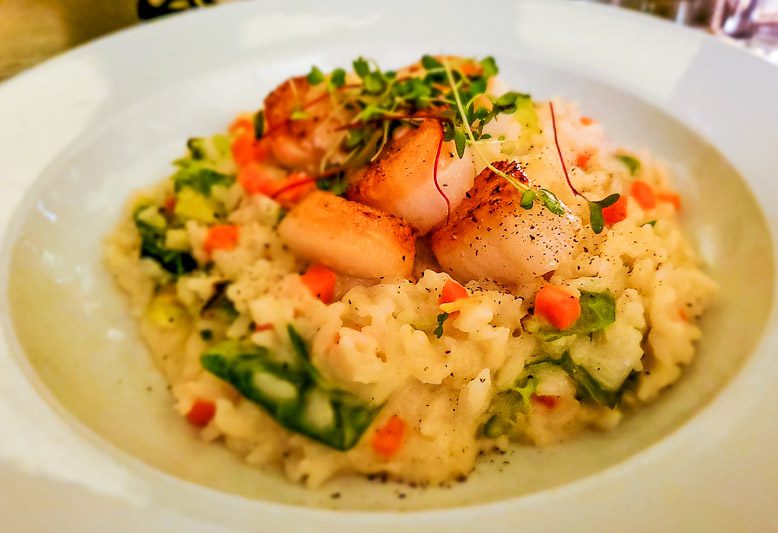 A plate of food, with sea scallops and Risotto