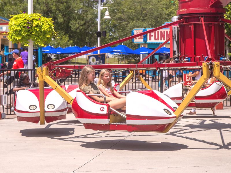 Two girls sitting on a spinning ride at Carowinds Amusement Park