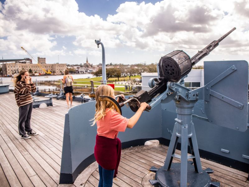 Child pretending to shoot a gun on a navy war ship