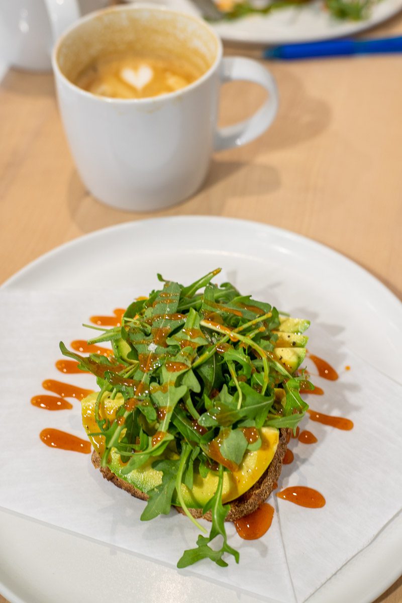 Avocado and arugula on toast and a cup of coffee