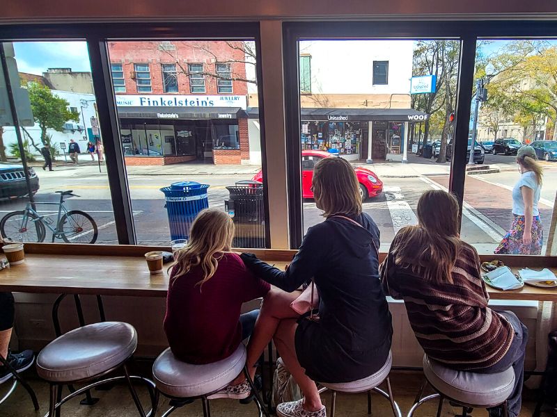 Mother and two daughters looking out a window at a restaurant