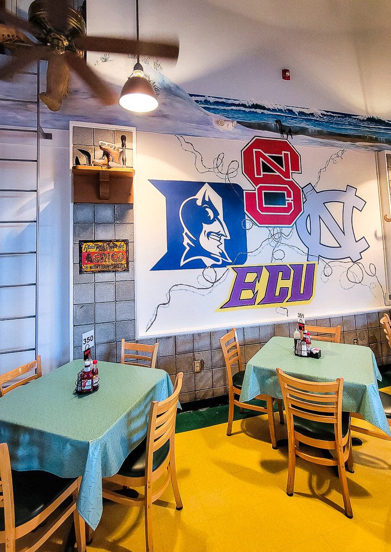 Tables and chairs in a cafe with college banners on the wall