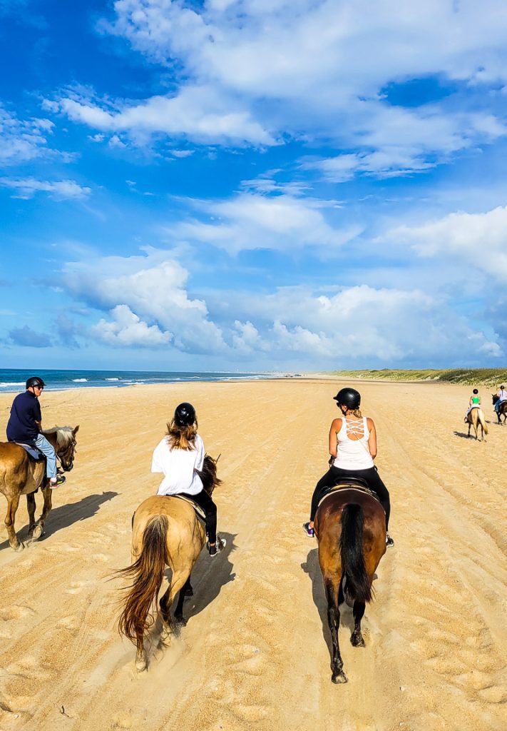Family of three riding a horse on a beach in the Outer Banks