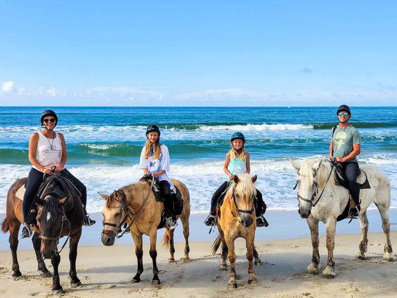 Family of four horse riding on the beach in the Outer Banks