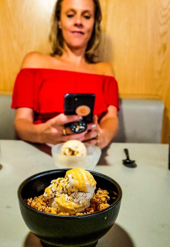 Lady taking a photo of ice cream in a restaurant