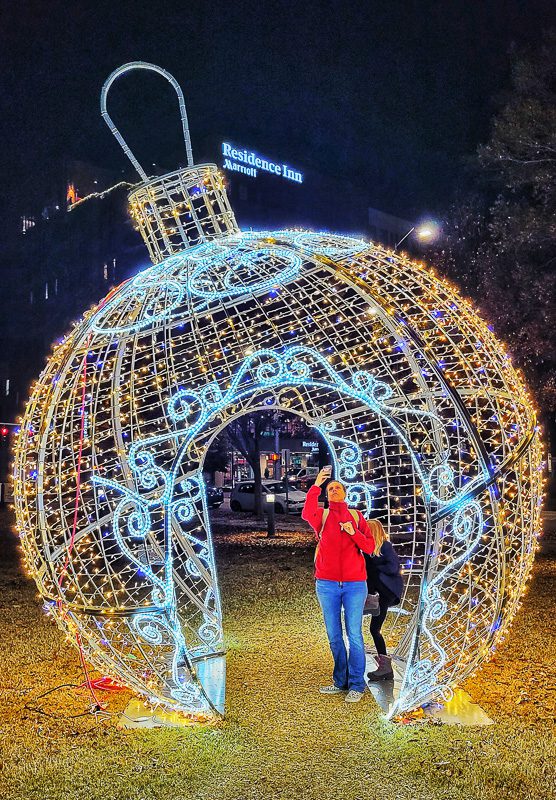 giant illuminated christmas ball ornament sculpture with people inside