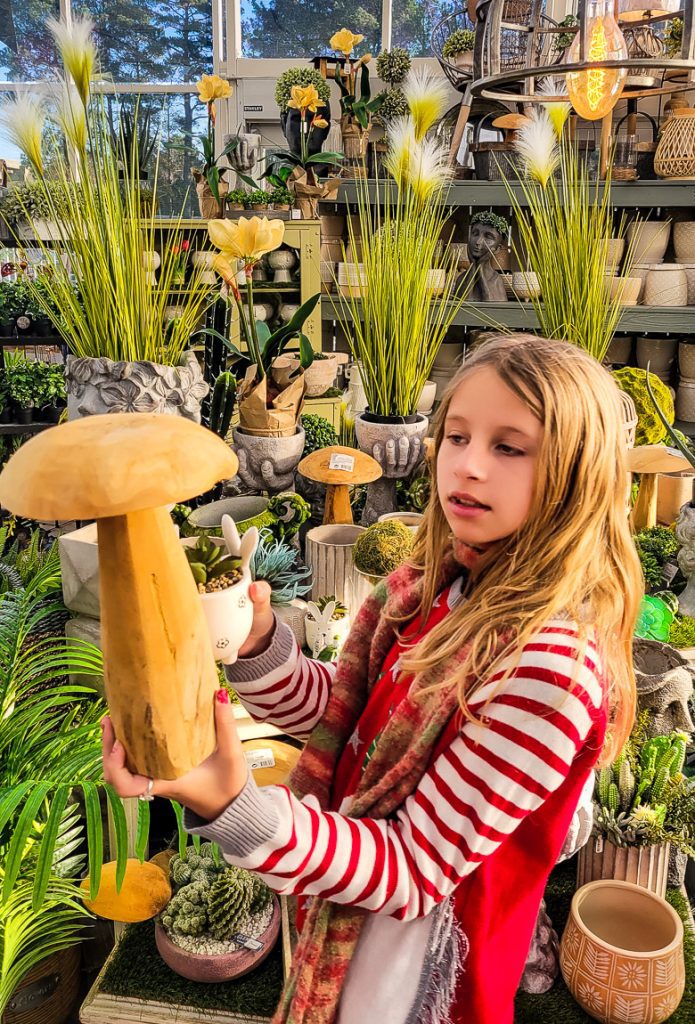 Girl holding up a wooden mushroom in a garden store