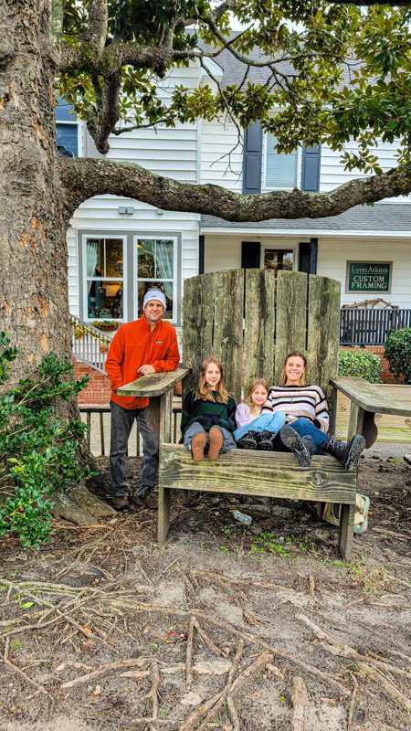 family sitting on giant chair under tree
