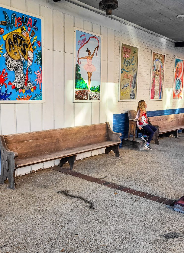 Girl sitting on a bench seat surrounded by murals