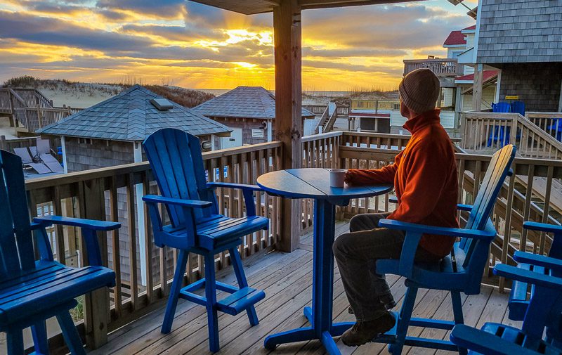 man looking at sunset from outer banks cottage deck