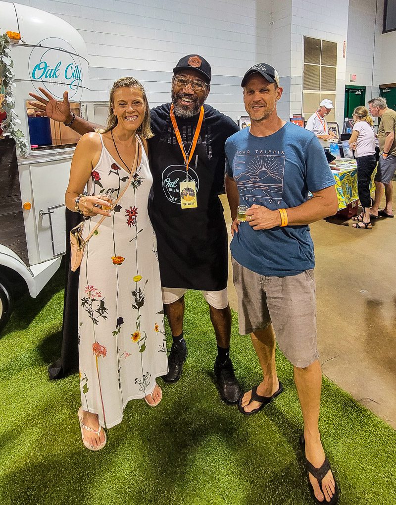Two men and a woman standing at a beer festival tasting beer