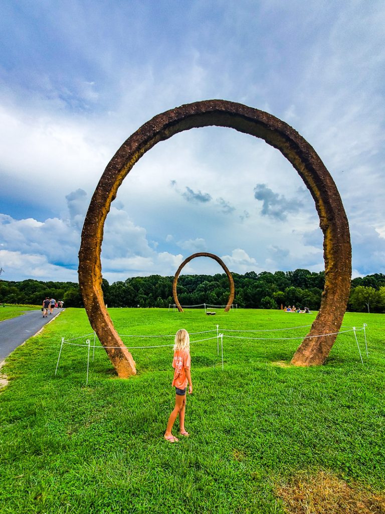 Young girl looking up at an art sculpture in the shape of a ring