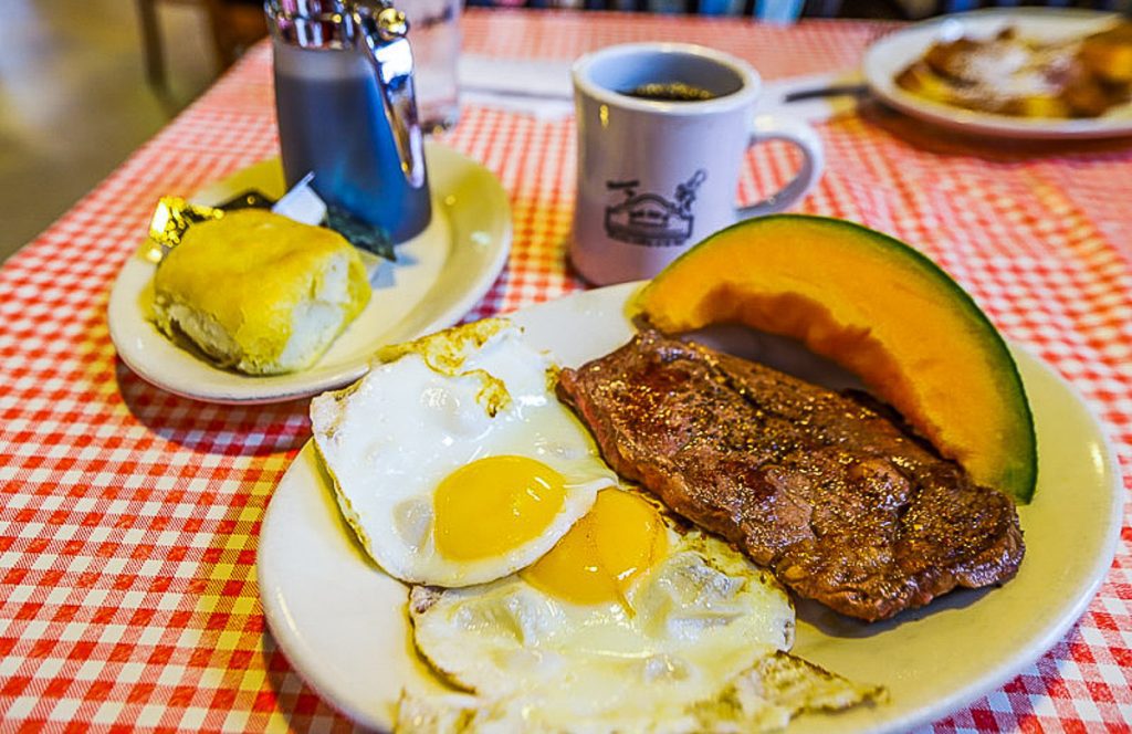Plate of steak and eggs and a black coffee