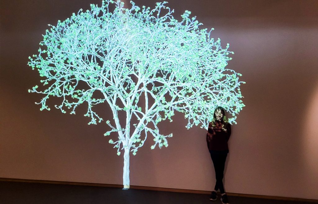 Young girl standing next to an art installation of a tree