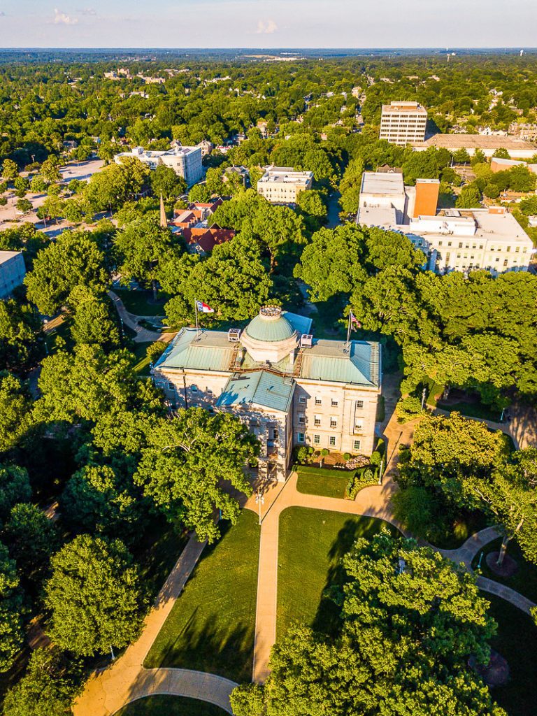 Aerial shot of the NC State Capitol building surrounded by oak trees