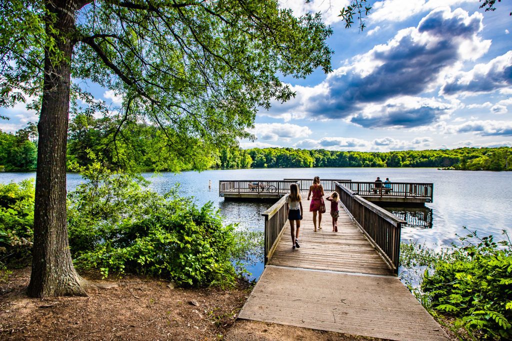 Mom and two daughters walking on a jetty at a lake
