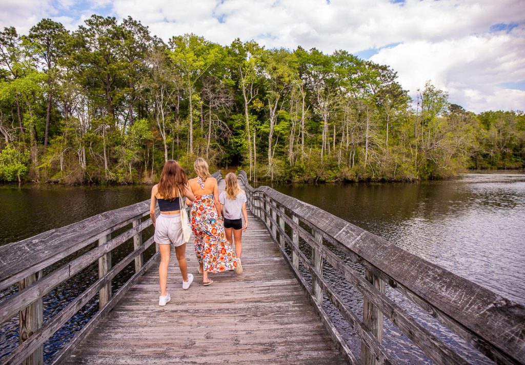 Mom and two daughters walking across a bridge over a lake