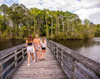 Mom and two daughters walking across a bridge over a lake