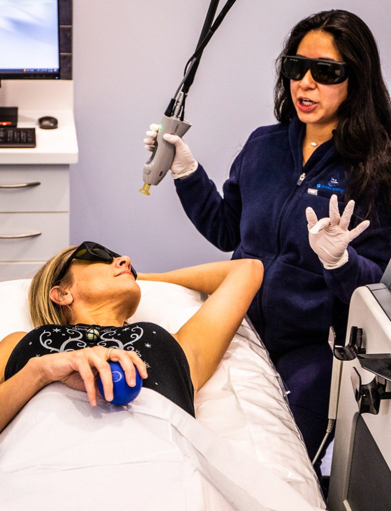 Lady laying on bed and female technician standing at a laser hair removal clinic