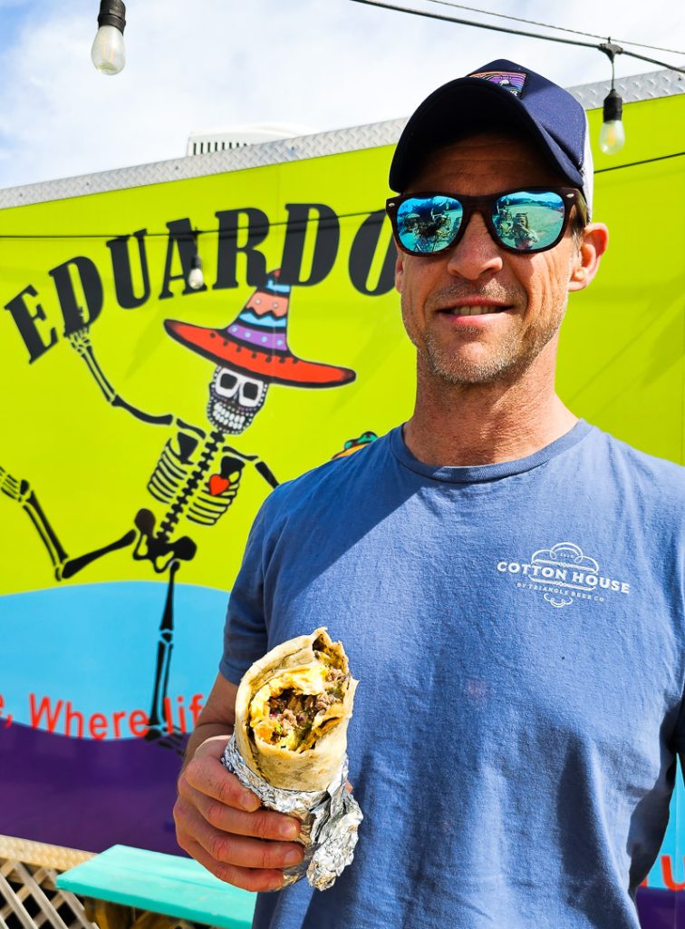 Man holding a burrito with a sign saying Eduardo's