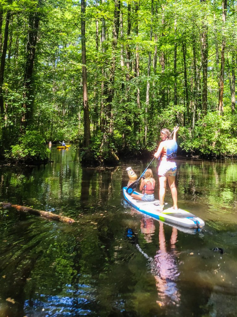 Mom and daughter paddling through a cyrpess swamp