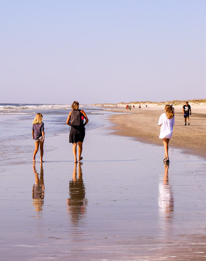 Mom and two daughters walking on a beach