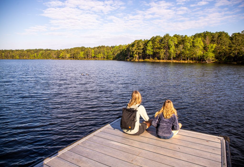 Mom and daughter sitting on a jetty at a lake