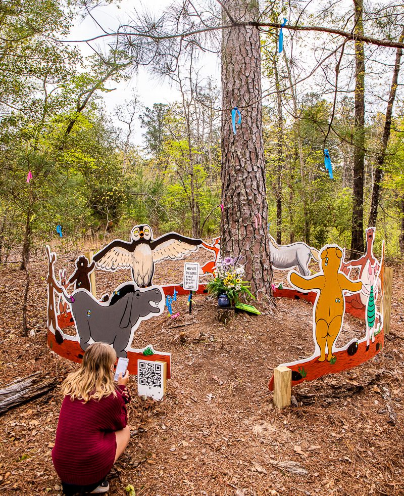 Girl looking at cardboard characters in a forest
