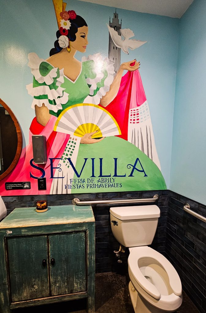 Toilet in bathroom with a Spanish mural on wall