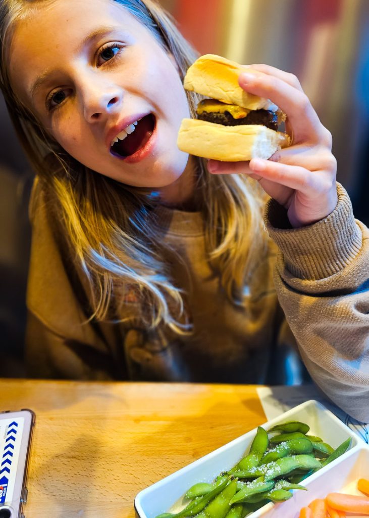 Girl holding a mini burger at Cowfish in North Hills