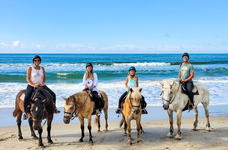 Family of four horse riding on the beach on the Outer Banks